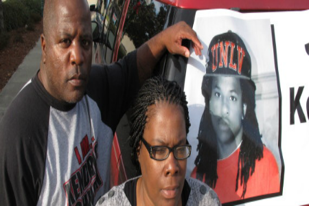 Kenneth and Jacquelyn Johnson stand next to a banner on their SUV showing their late son, Kendrick Johnson, on Dec. 13, 2013, in Valdosta, Ga. The 17 year old was found dead inside a rolled up gym mat at his high school Jan. 11, 2013, and authorities ruled it was a freak accident. Kendrick's family believes someone killed him and has been fighting to reopen the case. (AP Photo/Russ Bynum) | ASSOCIATED PRESS