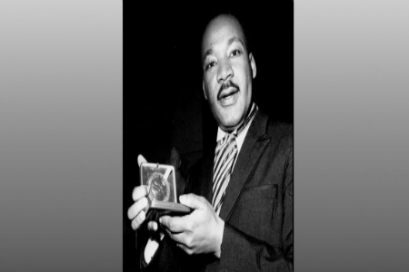 Dr. Martin Luther King, Jr. displays his 1964 Nobel Peace Prize medal, Oslo, Norway, on texture, partial graphic | ASSOCIATED PRESS
