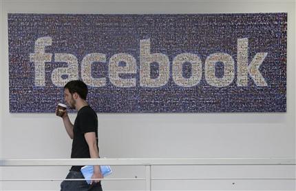 FILE - In this March 15, 2013, file photo, a Facebook employee walks past a sign at Facebook headquarters in Menlo Park, Calif. Facebook is giving more options to decide what happens to users’ accounts after they die. The world’s biggest online social network will now let users pick a trusted contact who can manage their account or elect to have the account deleted, the company announced, Thursday, Feb. 12, 2015. (AP Photo/Jeff Chiu, File)