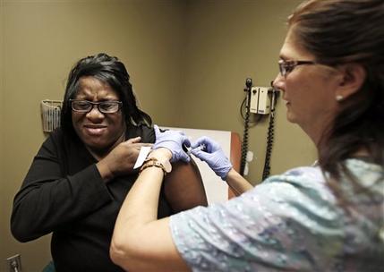 FILE - In this Jan. 10, 2013, nurse Debbie Smerk, left, administers a flu shot to Pamela Black at MetroHealth, in Cleveland. A new report shows this winter’s nasty flu season has peaked and is clearly retreating. The flu reached its highest levels around the beginning of January, and stayed there for weeks. The government report out Friday, Feb. 13, 2015, shows flu has become less widespread and less intense in the last couple of weeks. (AP Photo/Tony Dejak, File)