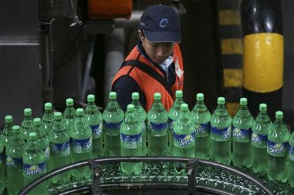 FILE - In this Feb. 24, 2011 file photo, a worker inspects bottles of Sprite at a Coca-Cola bottling plant in Cibitung , West Java, Indonesia. When beverage giants Coca-Cola and PepsiCo turned in their quarterly results last week, both blamed the dollar for cutting into their profits because, like most U.S. corporations, they rely on overseas sales. (AP Photo/Achmad Ibrahim, File)