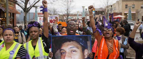 Brandon Marshall carries a photo of Anthony Hill as protesters march through the street demonstrating Hill's shooting death by a police officer, Wednesday, March 11, 2015, in Decatur, Ga. A police officer responding to reports of a suspicious person knocking on doors and crawling on the ground naked at an apartment complex Monday just outside Atlanta fatally shot Hill. Officer Robert Olsen shot Hill twice when the man began running toward him and didn't stop when ordered, DeKalb County Chief of | ASSOCIATED PRESS