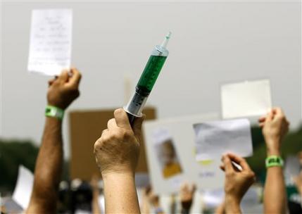 FILE - In this Wednesday, June 4, 2008 file photo, a woman holds up a syringe with symbolic green fluid during a rally on Capitol Hill in Washington calling for the elimination of what demonstrators say are toxins in children's vaccines. Parents have been nervous about vaccines for as long as vaccines have been around. Opposition seemed to plummet for several decades, as vaccines got better and succeeded in beating back diseases, but parental concern has seemed to be on an upswing in the last 20 years. (AP Photo/Jose Luis Magana)