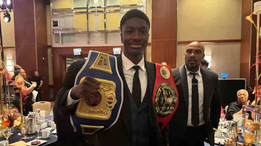 A young man at the UNCF AMI Gala shows off his championship boxing belts 